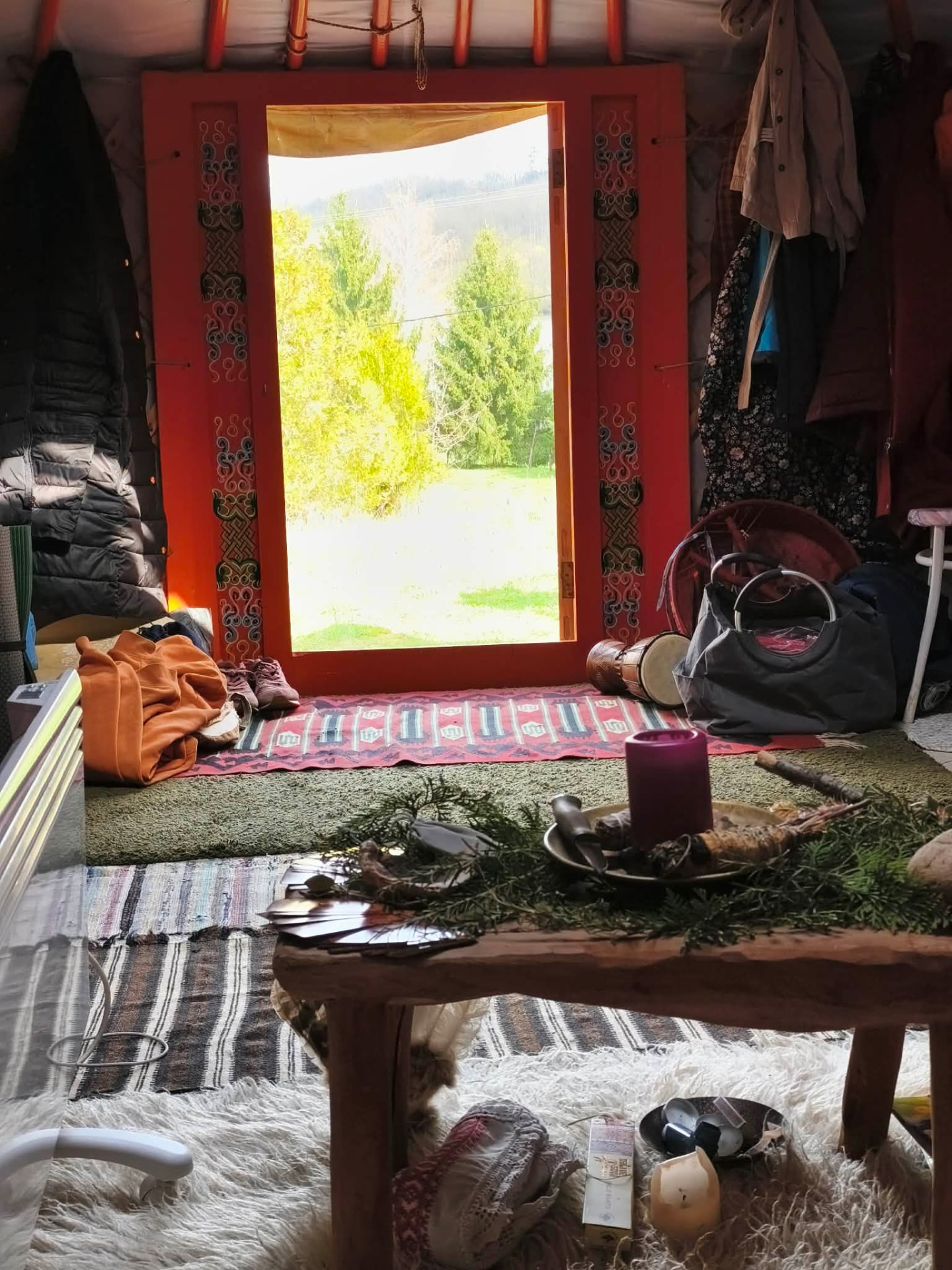 A jurta belső tere kilátással a kertre, dobbal és gyertyával